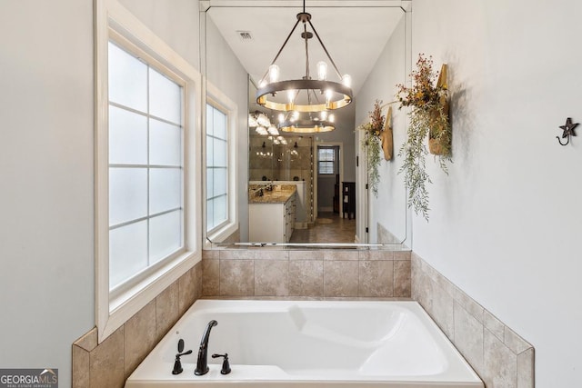 bathroom with vanity, a notable chandelier, and a bath