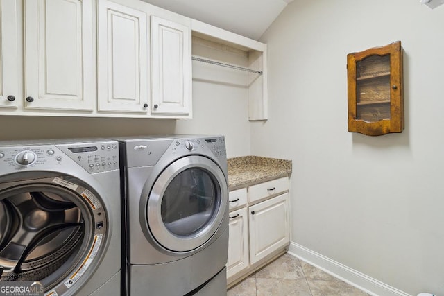 laundry room with washing machine and dryer, cabinets, and light tile patterned floors