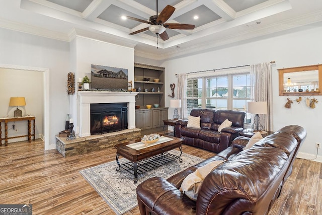 living room featuring crown molding, a stone fireplace, and coffered ceiling