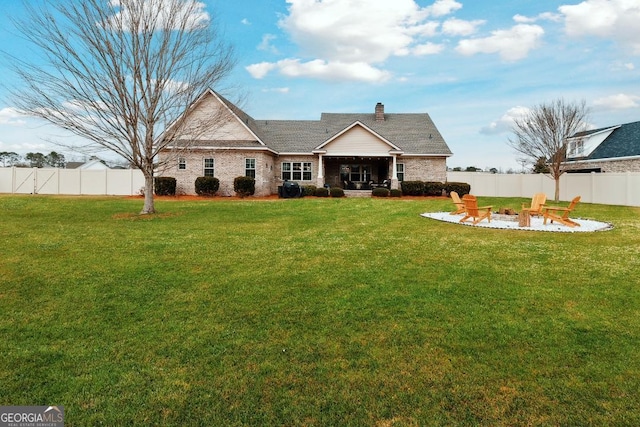 back of house featuring a lawn, a patio area, and a fire pit