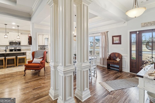 entrance foyer featuring dark wood-type flooring, ornate columns, ornamental molding, and sink