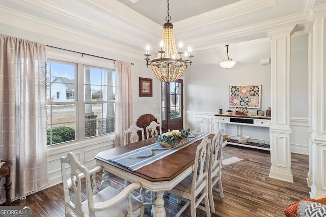 dining area with ornate columns, an inviting chandelier, a raised ceiling, dark hardwood / wood-style floors, and crown molding