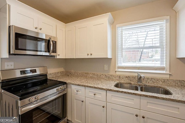 kitchen featuring white cabinets, sink, light stone countertops, and stainless steel appliances