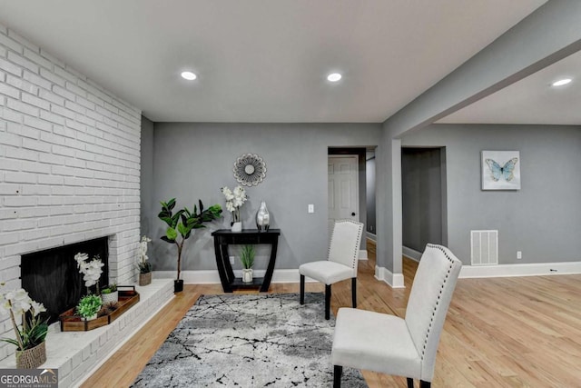 living area with wood-type flooring and a brick fireplace