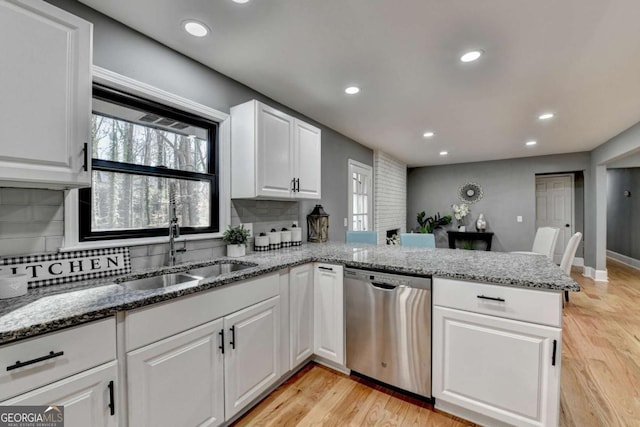 kitchen featuring dishwasher, sink, backsplash, kitchen peninsula, and white cabinets