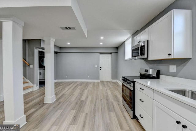 kitchen with light wood-type flooring, white cabinetry, sink, and appliances with stainless steel finishes