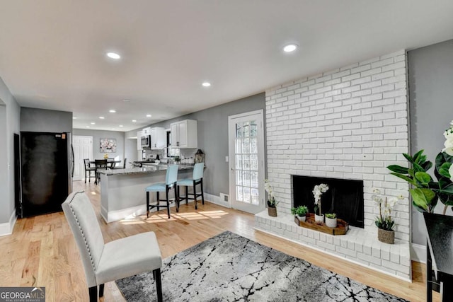 living room featuring light hardwood / wood-style floors and a brick fireplace