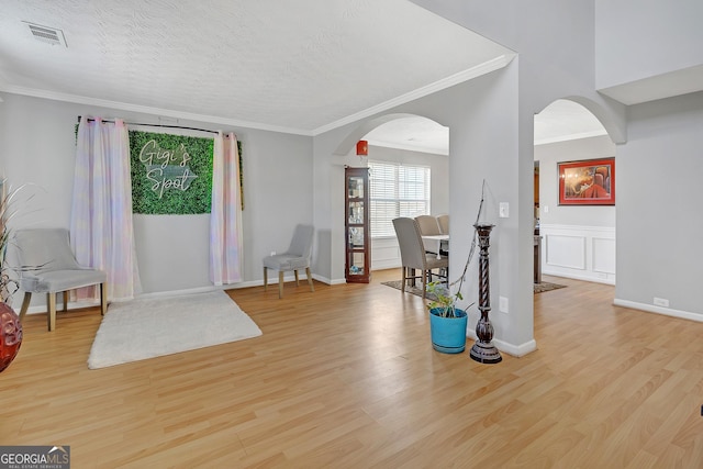 foyer entrance with crown molding, a textured ceiling, and light wood-type flooring