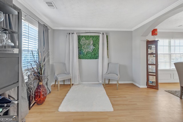 sitting room featuring ornamental molding, light hardwood / wood-style floors, and a textured ceiling