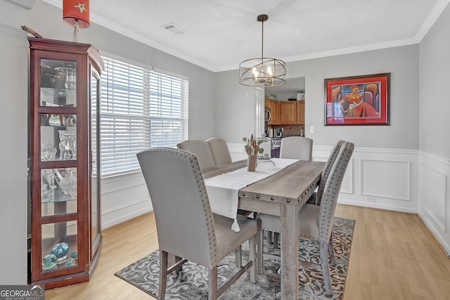 dining room featuring crown molding, an inviting chandelier, and light wood-type flooring