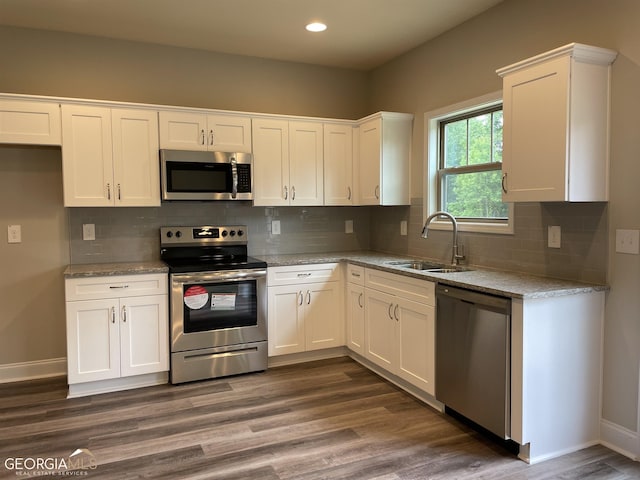 kitchen featuring light stone countertops, appliances with stainless steel finishes, dark hardwood / wood-style flooring, sink, and white cabinetry