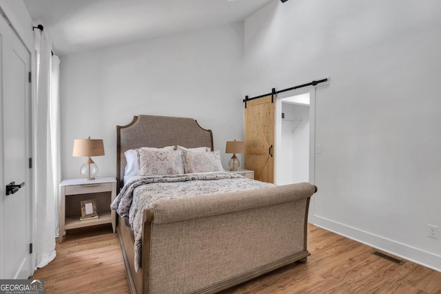 bedroom with a barn door and light hardwood / wood-style flooring