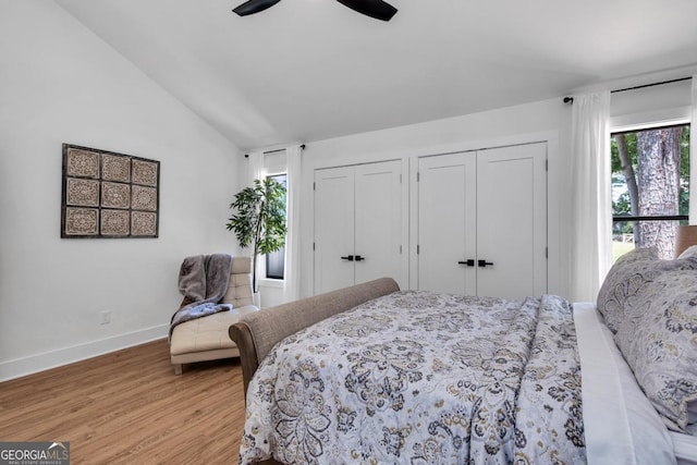 bedroom featuring hardwood / wood-style floors, two closets, ceiling fan, and lofted ceiling