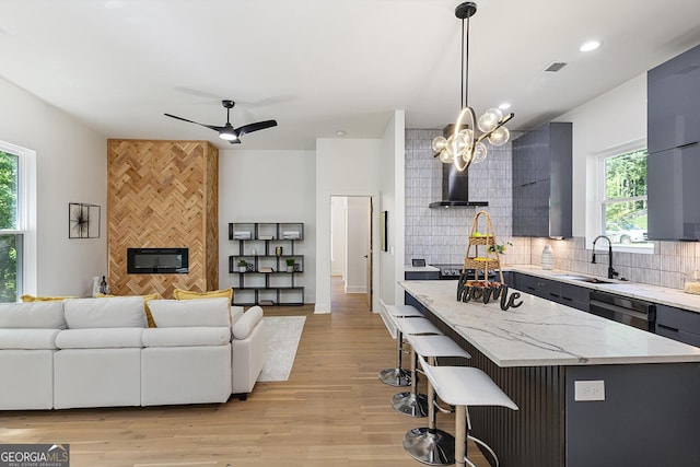 kitchen with a breakfast bar area, a kitchen island, sink, black dishwasher, and decorative light fixtures