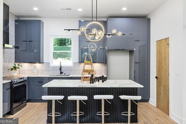 kitchen featuring a kitchen island, a kitchen bar, light wood-type flooring, and black electric range oven