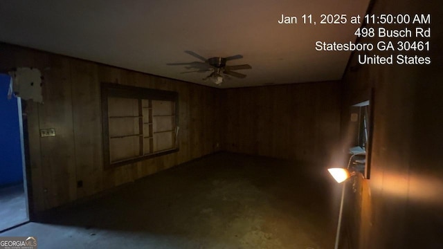 empty room with ceiling fan and wooden walls