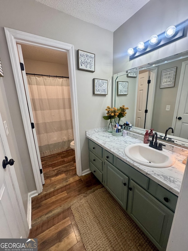 bathroom with hardwood / wood-style flooring, vanity, a textured ceiling, and toilet