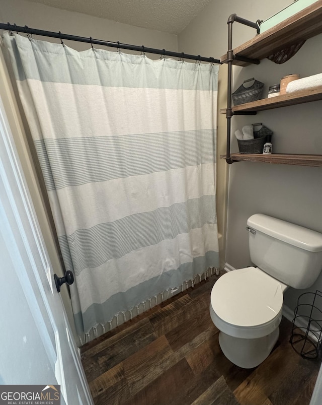 bathroom with hardwood / wood-style flooring, toilet, a textured ceiling, and a shower with shower curtain