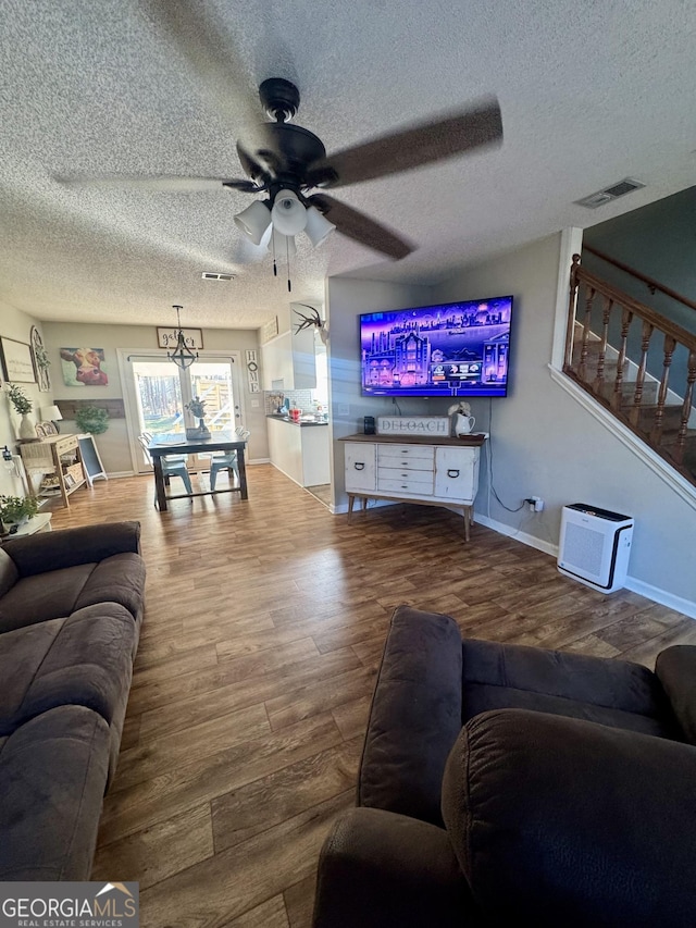 living room with a textured ceiling, hardwood / wood-style flooring, and ceiling fan