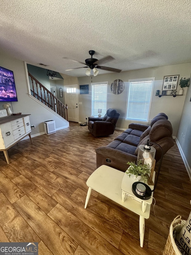 living room with ceiling fan, wood-type flooring, and a textured ceiling