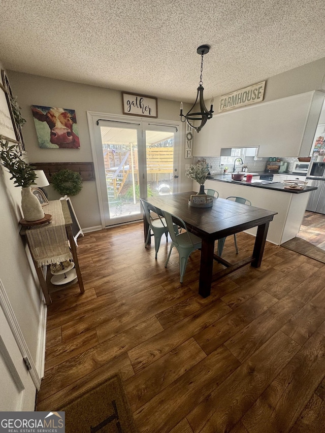 dining space with sink, dark hardwood / wood-style flooring, and a textured ceiling