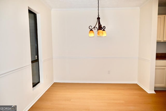 unfurnished dining area featuring light hardwood / wood-style floors, an inviting chandelier, and crown molding