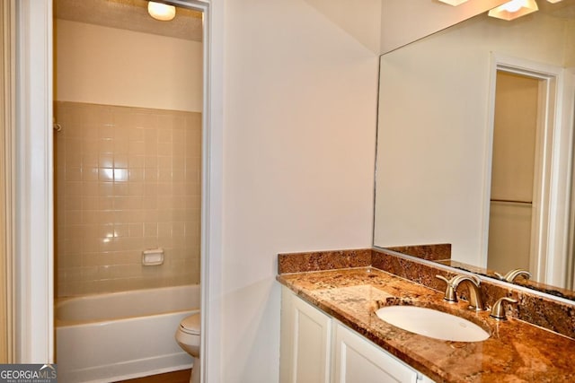 full bathroom featuring tiled shower / bath, vanity, and toilet