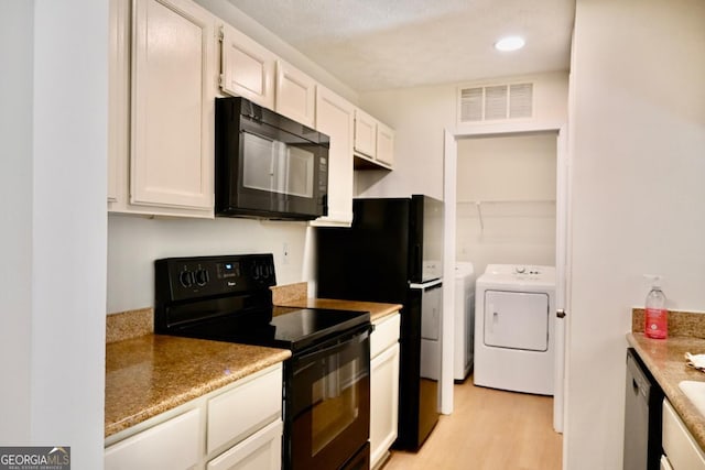 kitchen featuring washing machine and clothes dryer, white cabinetry, light stone countertops, light hardwood / wood-style floors, and black appliances