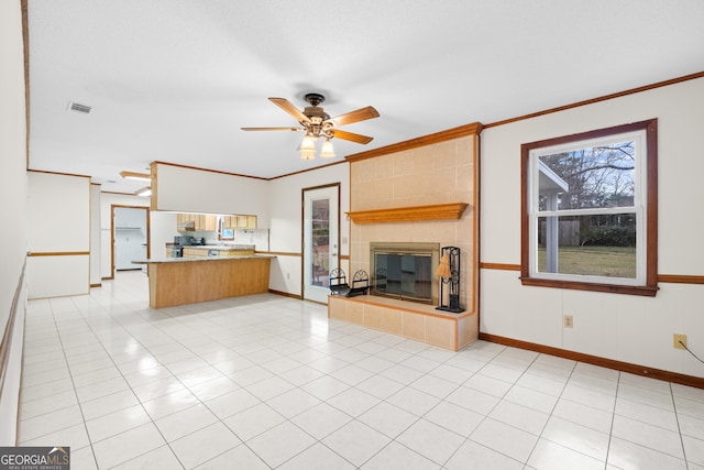 unfurnished living room featuring a tile fireplace, ceiling fan, light tile patterned floors, and ornamental molding