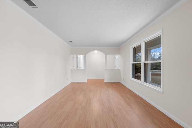 unfurnished room featuring light hardwood / wood-style floors, ornamental molding, and a textured ceiling