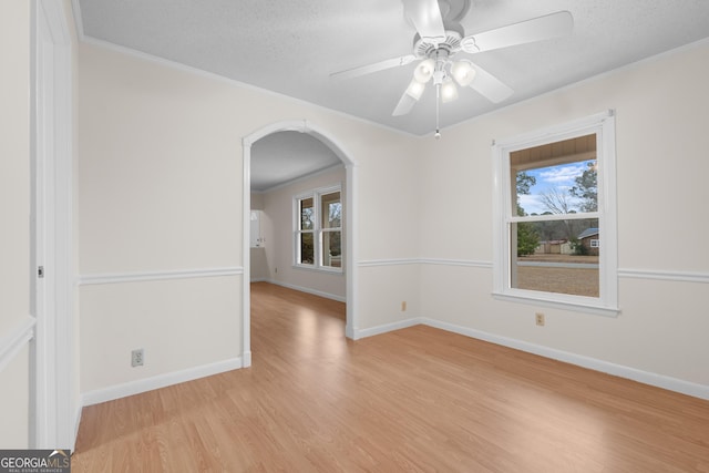 empty room with ceiling fan, ornamental molding, a textured ceiling, and light wood-type flooring