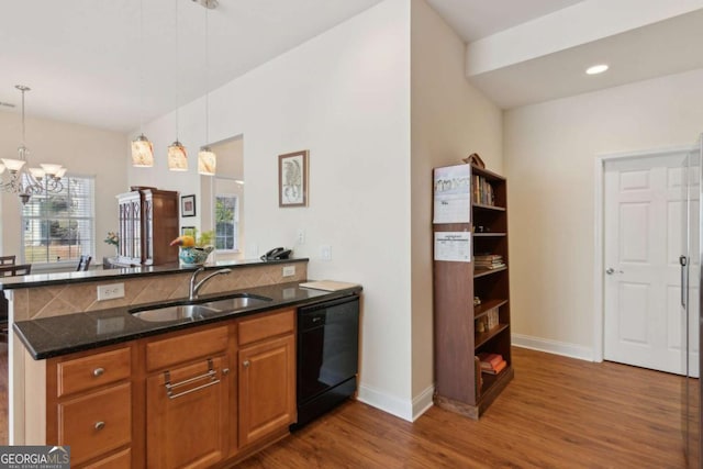 kitchen featuring kitchen peninsula, sink, dark stone countertops, and black dishwasher