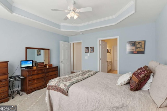 bedroom featuring ceiling fan, a raised ceiling, ensuite bathroom, light carpet, and ornamental molding