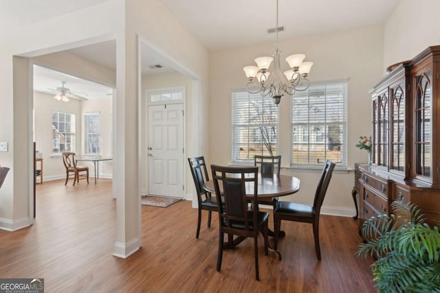 dining space featuring ceiling fan with notable chandelier and wood-type flooring