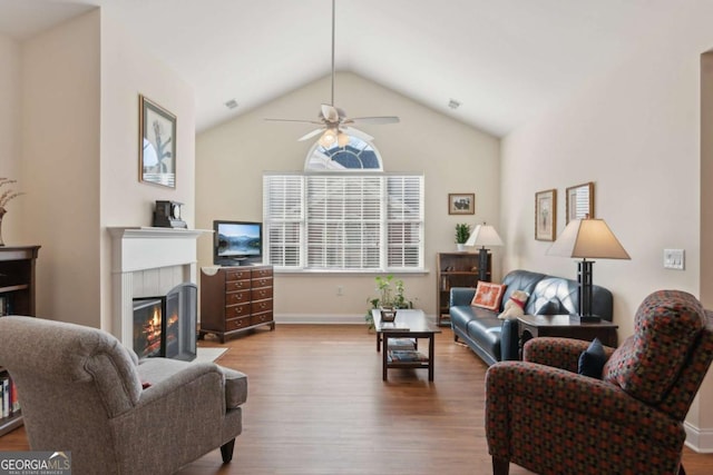 living room with hardwood / wood-style flooring, ceiling fan, a tile fireplace, and vaulted ceiling