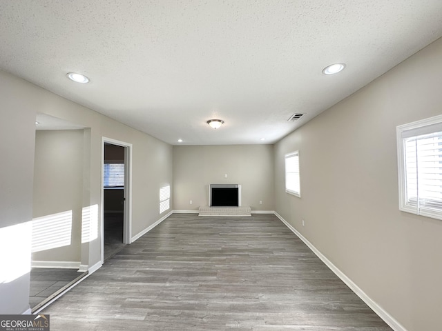 unfurnished living room featuring a textured ceiling, light hardwood / wood-style floors, and a fireplace