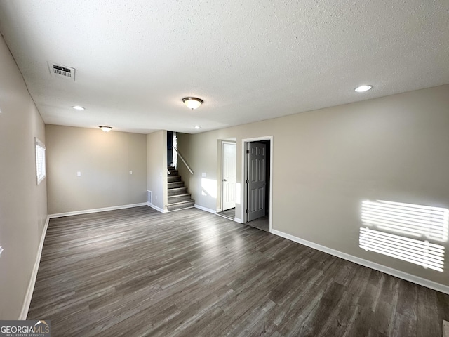 spare room featuring a textured ceiling and dark wood-type flooring