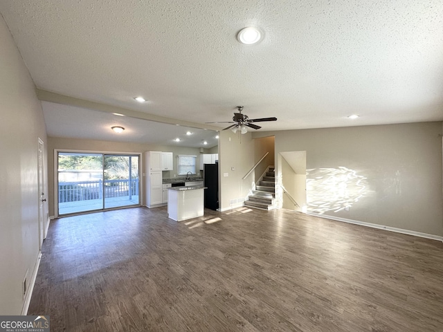 unfurnished living room featuring ceiling fan, dark hardwood / wood-style flooring, a textured ceiling, and sink