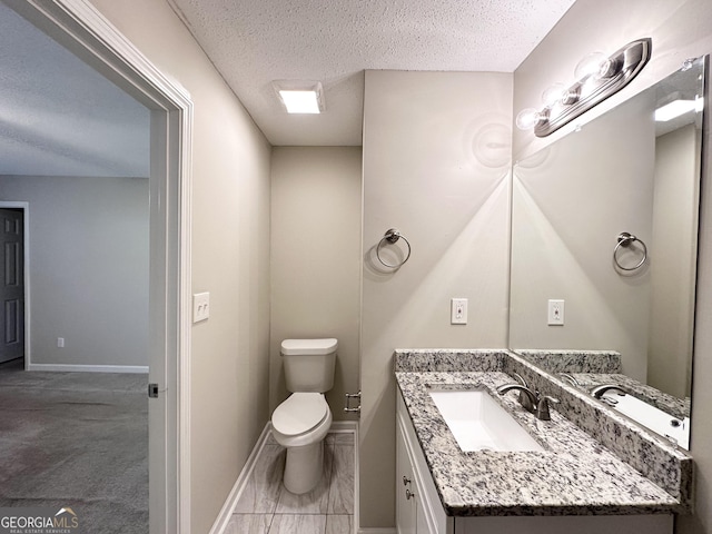 bathroom featuring vanity, a textured ceiling, and toilet