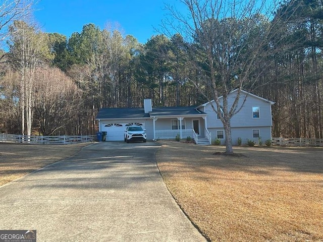 view of front facade featuring covered porch, a front yard, and a garage