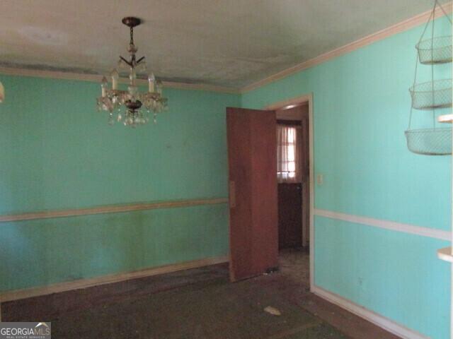 unfurnished room featuring ornamental molding and an inviting chandelier