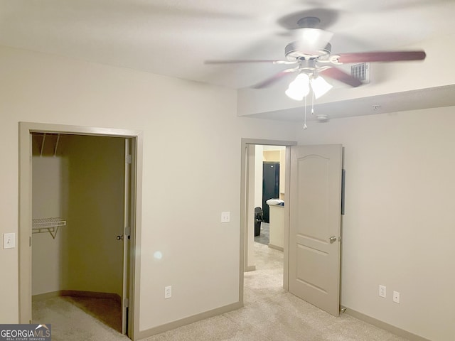 unfurnished bedroom with ceiling fan, light colored carpet, a spacious closet, and a closet