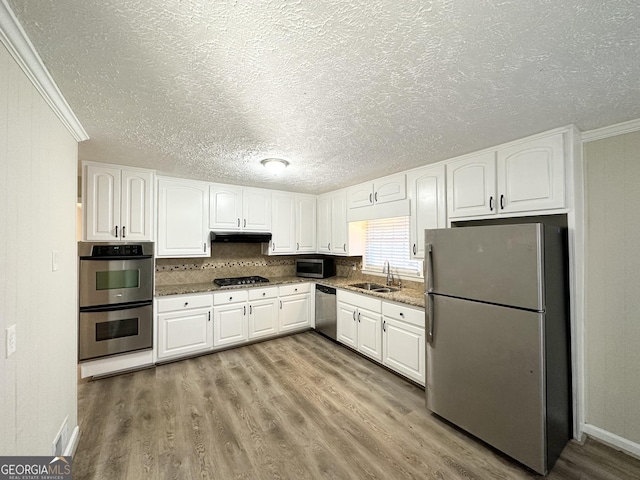 kitchen with sink, white cabinets, stainless steel appliances, and ornamental molding