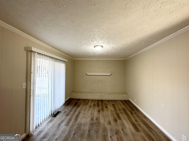 empty room featuring a textured ceiling, dark hardwood / wood-style floors, crown molding, and brick wall