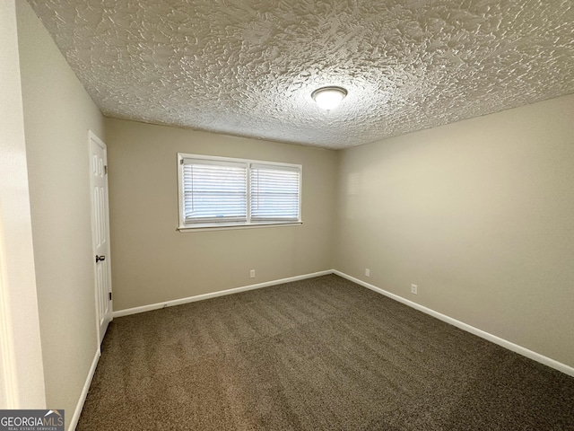 empty room with a textured ceiling and dark colored carpet