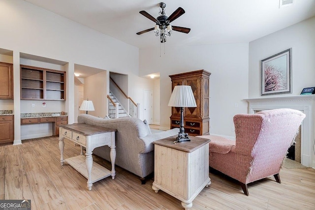 living room featuring ceiling fan, light hardwood / wood-style floors, and lofted ceiling