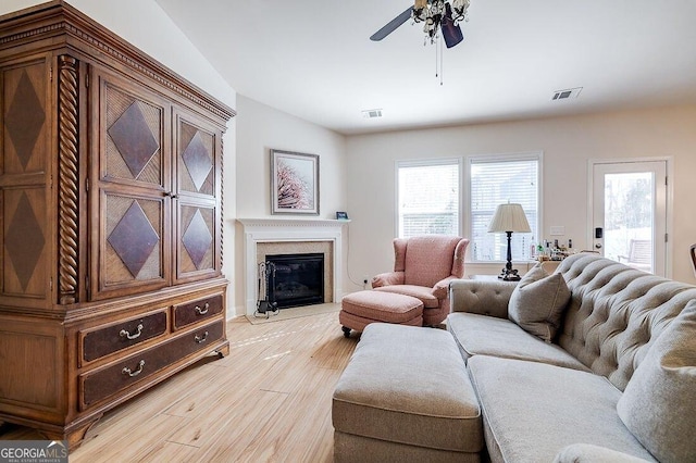 living room with ceiling fan, a fireplace, and light hardwood / wood-style floors