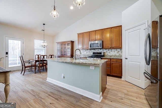 kitchen with a center island with sink, decorative light fixtures, sink, and appliances with stainless steel finishes