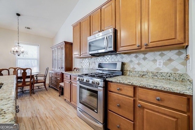 kitchen with backsplash, a notable chandelier, lofted ceiling, and appliances with stainless steel finishes