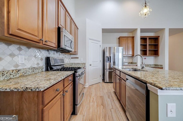 kitchen featuring sink, tasteful backsplash, light hardwood / wood-style flooring, pendant lighting, and appliances with stainless steel finishes